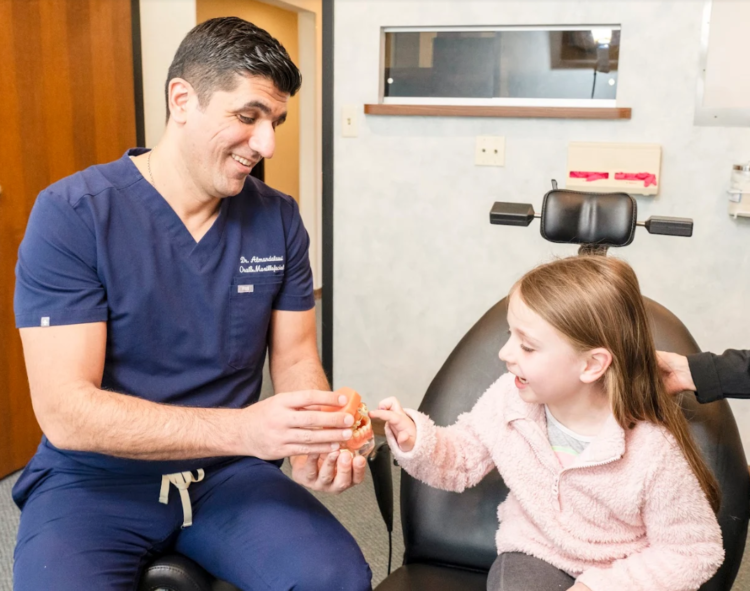 Dr. Mohammed Almandalawi with a small girl in examining room