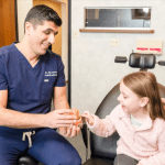  Dr. Mohammed Almandalawi with a small girl in examining room 