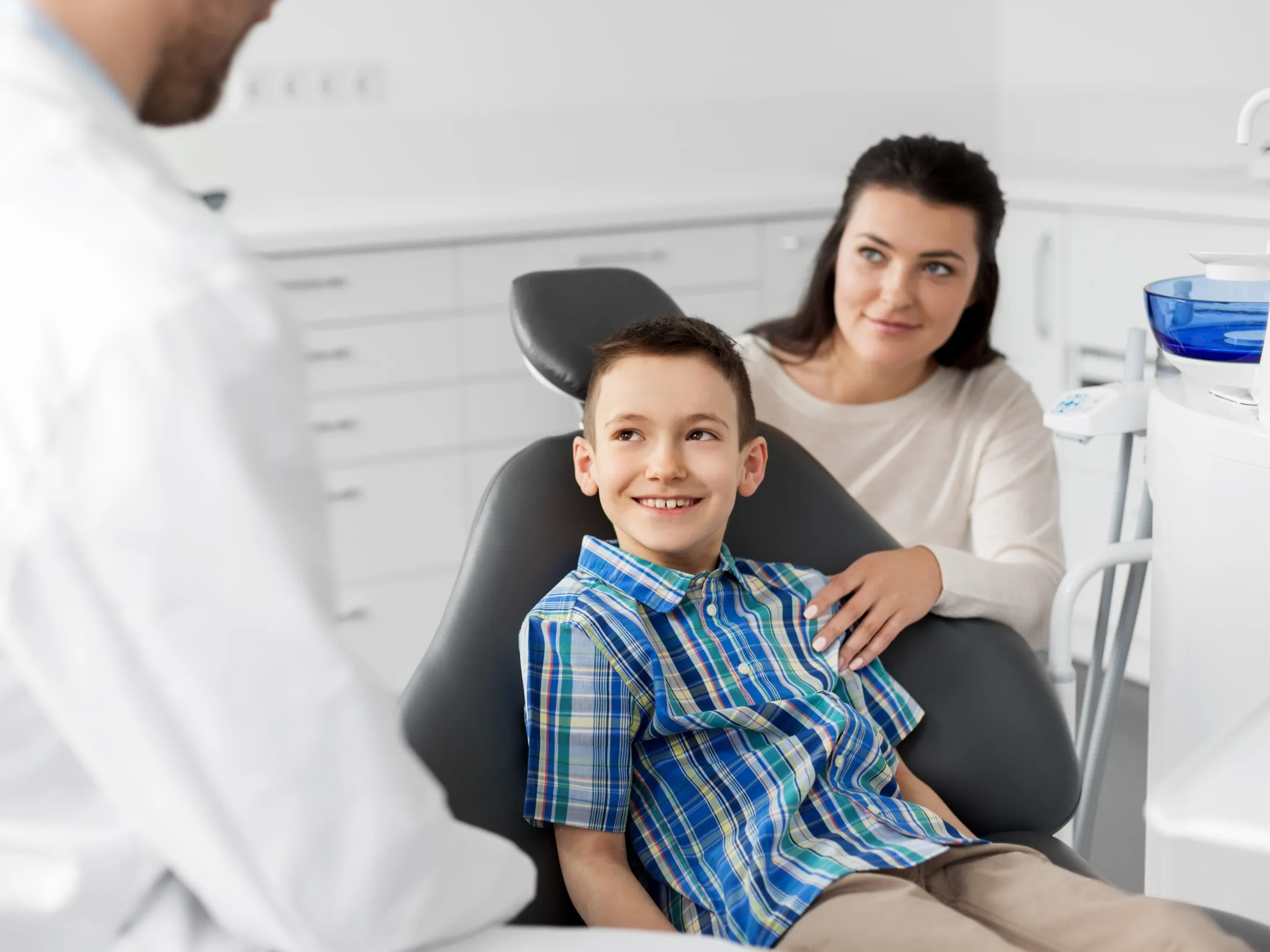 child smiling in chair and mother next to him