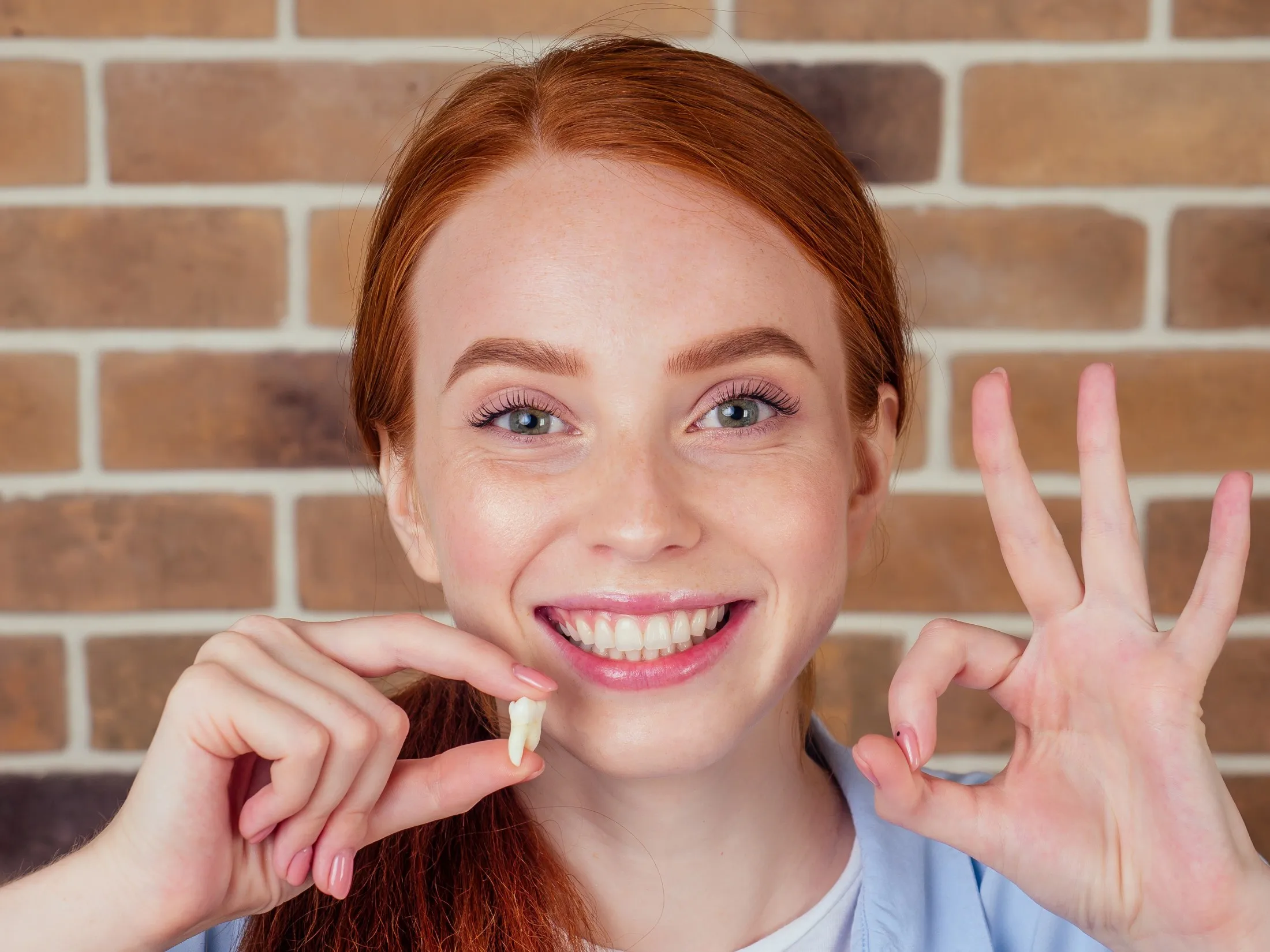 girl holding tooth doing the okay sign